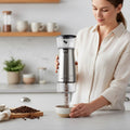 Woman using a manual coffee grinder in a kitchen setting